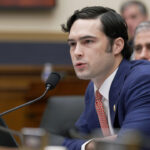 U.S. Rep. Brandon Gill leans forward in a blue suit and red tie.