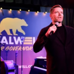 Eric Swalwell on stage with a microphone.