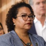 California Assemblymember Mia Bonta looks on as Gov. Gavin Newsom stands in the background.