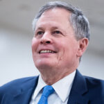 Sen. Steve Daines stands and smiles.