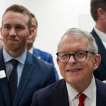 Gov. Mike DeWine appears for a factory tour while smiling.