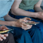 Three teen boys are seen looking at their smart phones.