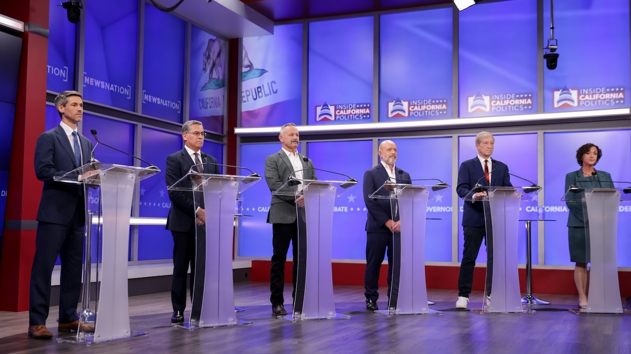 Six California gubernatorial candidates stand at podiums during a debate on April 22, 2026.