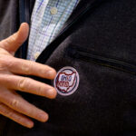 A man places his hand by the "Ohio Voted" sticker on his suit jacket.