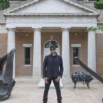 A man standing between two statues