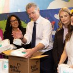 Gov. Gavin Newsom opens a box of diapers.