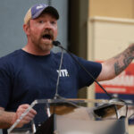 Senate candidate Graham Platner gestures with his arm out as he speaks at an event.