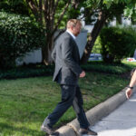 Graham Platner, candidate for Senate, walks in front of a woman companion, with police officers to his side.