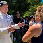 Spencer Pratt in a white jacket speaks to a voter.
