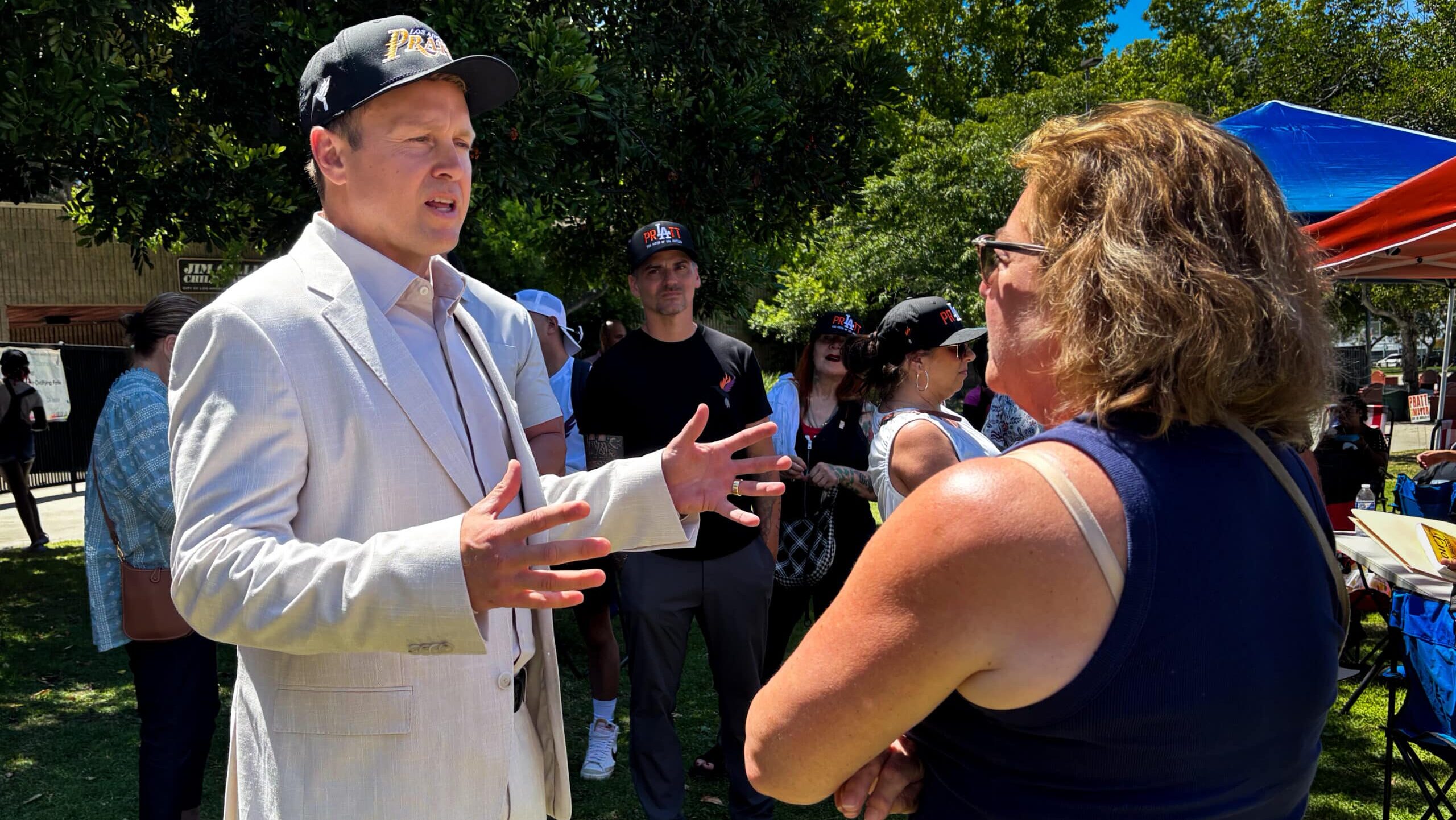 Spencer Pratt in a white jacket speaks to a voter.
