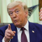 President Donald Trump gestures from his desk in the Oval Office.