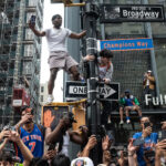 Fans can be seen climbing a lamp post during a parade.