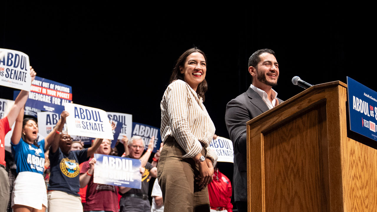 Michigan Democratic candidate for Senate Abdul El-Sayed and U.S. Rep. Alexandria Ocasio-Cortez stand together at a podium.