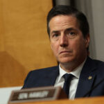 Sen. Bernie Moreno sits at the podium and stares out straight ahead during a committee hearing.