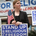 People holding signs that say "stand up for religious freedom"