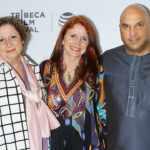 Abigail Disney, Jodie Evans and Neville Roy Singham stand in front of a "Tribeca Film Festival" backdrop.
