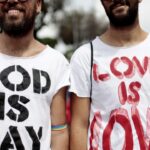 Men wearing shirts that say "God is gay" and "Love is love"