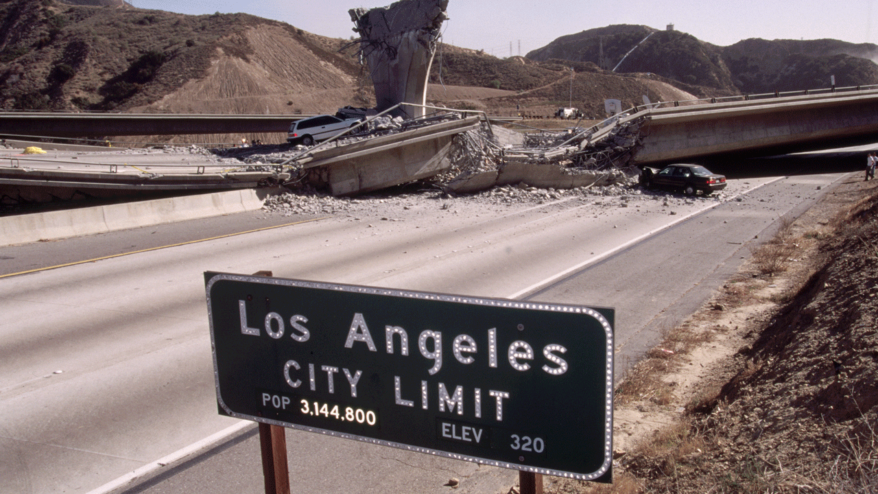 Home 2 A collapsed freeway overpass blocks a deserted highway near a Los Angeles City Limit sign, with hills in the background and one car parked near the rubble.