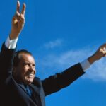 Richard Nixon gives two-armed victory salute
