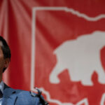 Ohio Secretary of State Frank LaRose speaks in front of a red banner with an elephant inside a map of Ohio.
