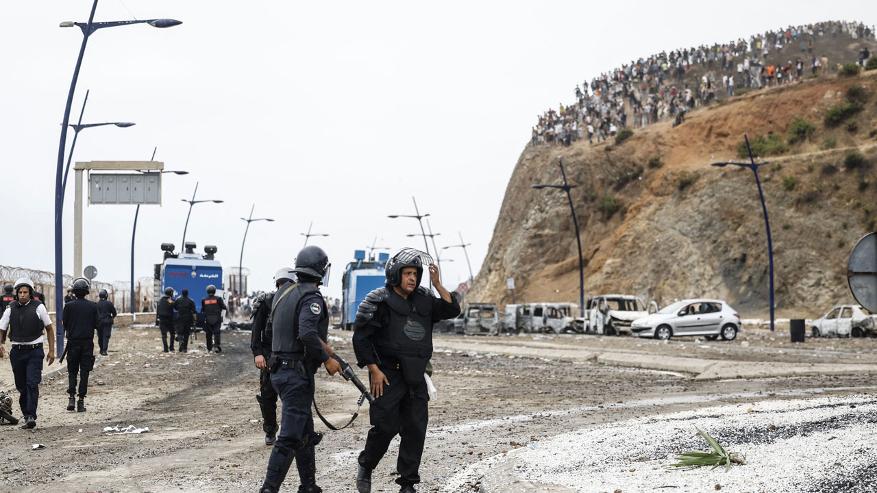 Moroccan security forces stand at the site of clashes with migrants attempting to cross into Spain's North African enclave of Ceuta near the town of Fnideq.
