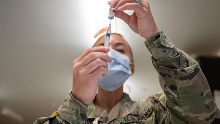 A Preventative Medicine Services technician fills a syringe with a Janssen COVID-19 vaccine.