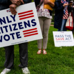 Attendees hold 'Only Citizens Vote' signs at a rally.