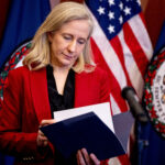 Gov. Abigail Spanberger flips through a folder at a press conference announcing there is a deal to authorize cannabis sales and put the legislation in the upcoming budget, Tuesday, June 16, 2026, in Richmond, Va. (Mike Kropf/Richmond Times-Dispatch via Getty Images)