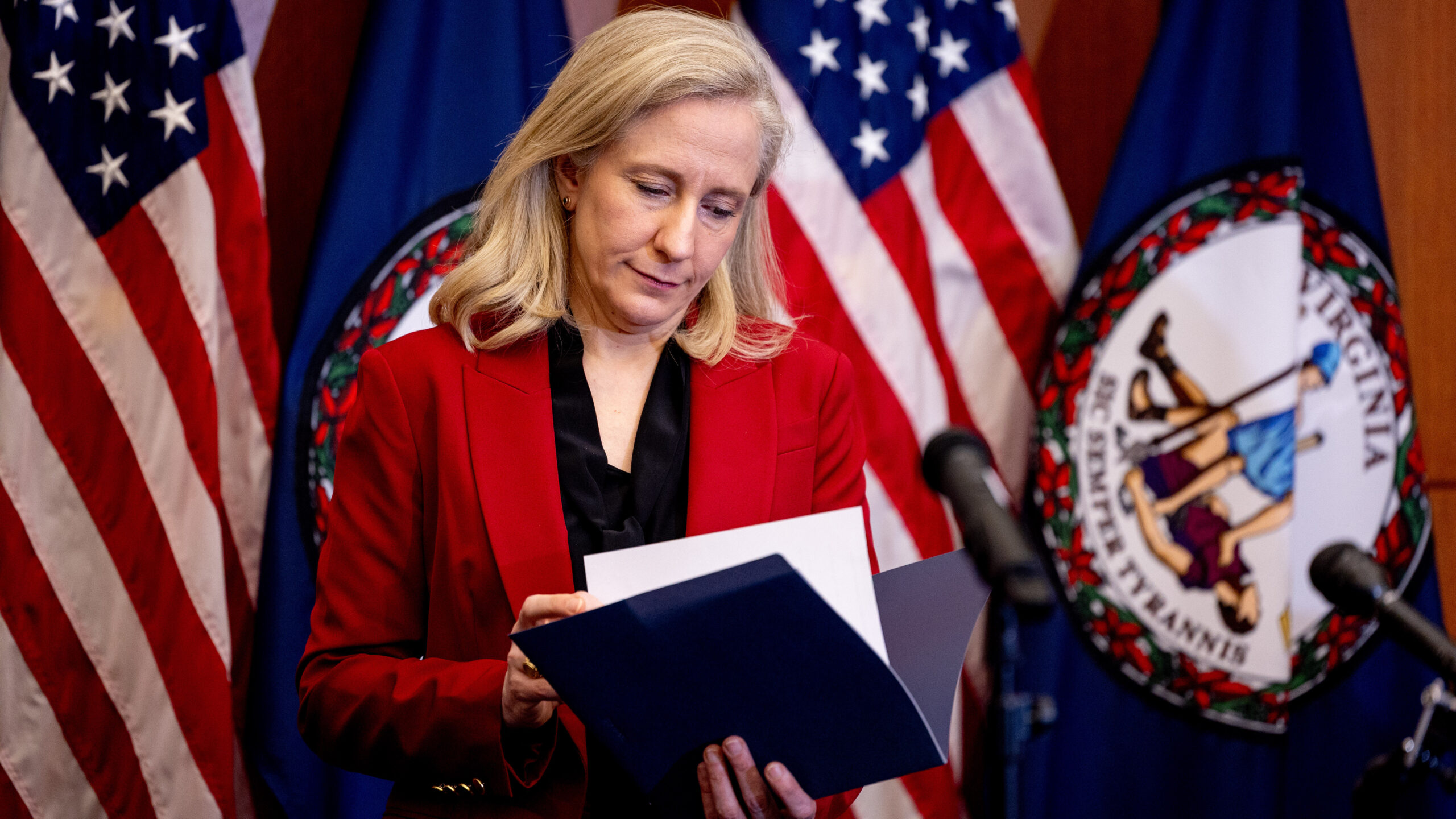 Gov. Abigail Spanberger flips through a folder at a press conference announcing there is a deal to authorize cannabis sales and put the legislation in the upcoming budget, Tuesday, June 16, 2026, in Richmond, Va. (Mike Kropf/Richmond Times-Dispatch via Getty Images)