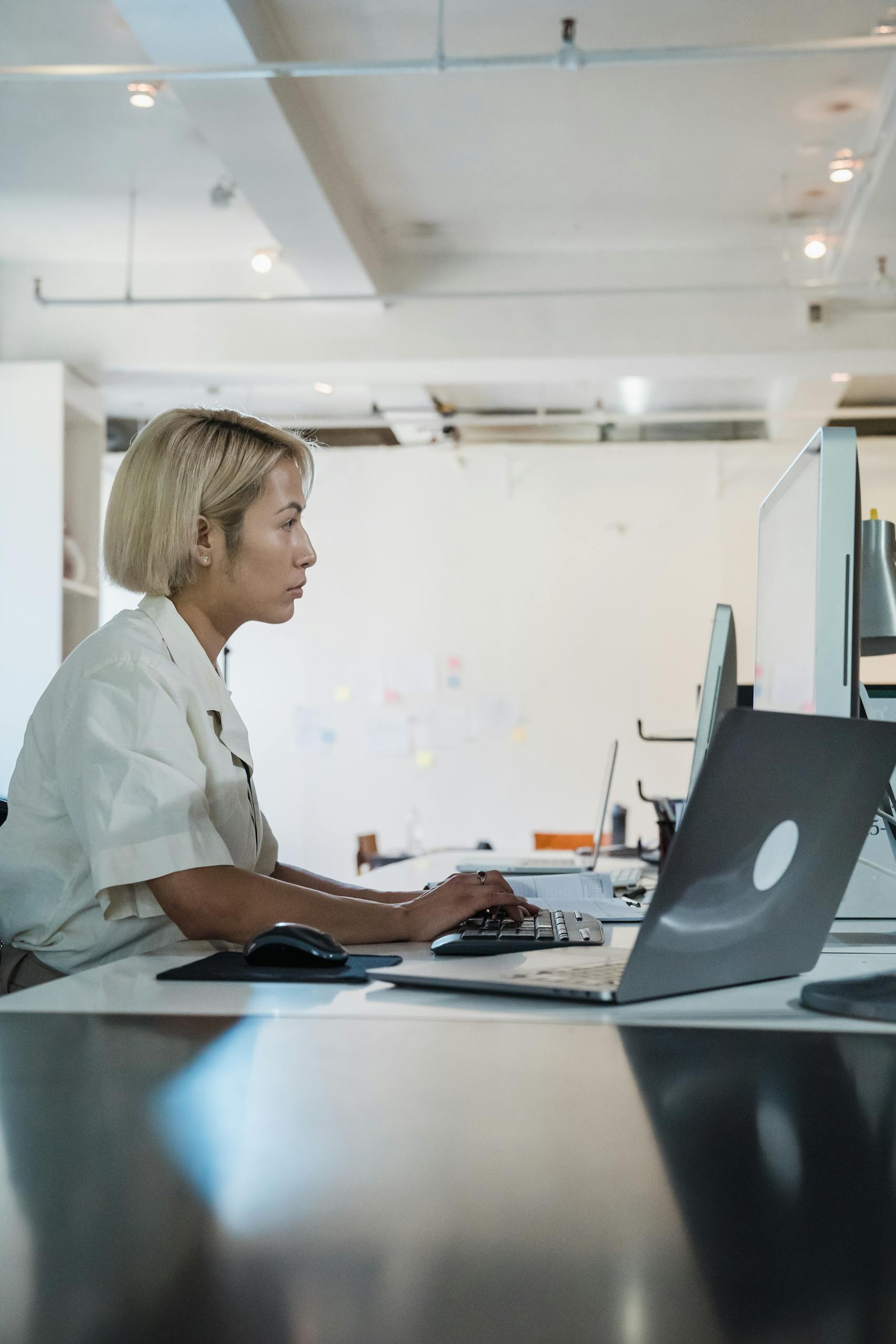 A woman working intently on a computer in a bright, modern office setting.