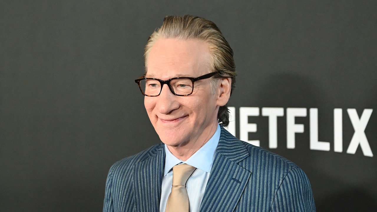 Home 5 Bill Maher smiles in front of a black backing with white writing that reads "Netflix."