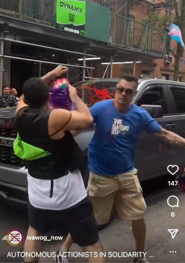 Time to Wave ‘Queer’ Goodbye 2 Two people are fighting on a city street; one is wearing a blue shirt and khaki shorts, and the other has a black tank top and neon green pack. A truck and bystanders are visible in the background.