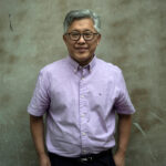 Pastor Ezra Jin stands against a grey background.