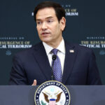 A man in a suit speaks at a podium with the U.S. Department of State seal, in front of a backdrop that reads The Resurgence of Political Terrorism.